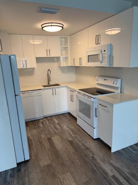 A modern kitchen features white cabinetry, stainless steel appliances, quartz countertops, and wood-look flooring — 751 Pine Drive # 104, Pompano Beach FL 33060, POMPANO BEACH, FL
