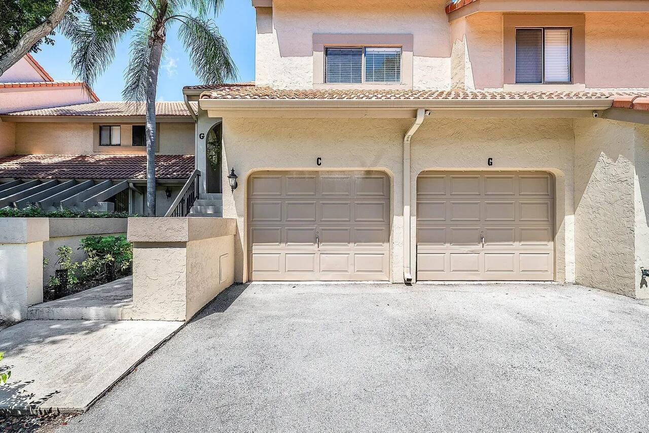 A two-story townhouse exterior features two beige garage doors labeled C and G — 5520 Coach House Circle # G, Boca Raton FL 33486, BOCA RATON, FL