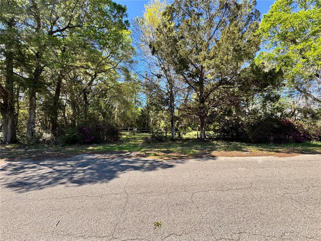 A paved road leads to a gated entrance of a wooded, undeveloped residential lot — 1336 NE 191ST TERRACE, HAWTHORNE, FL