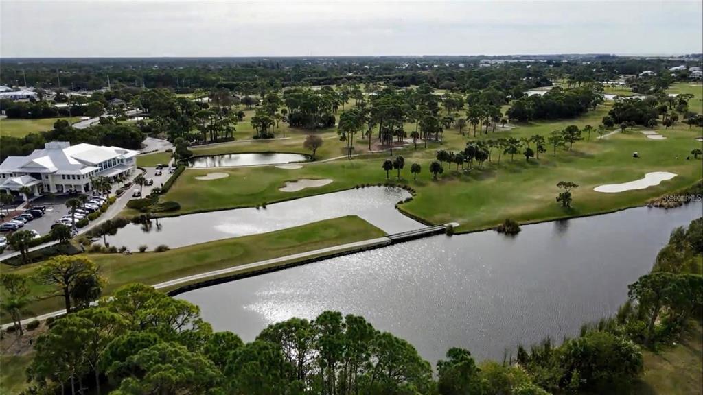 An aerial view of a golf course featuring a clubhouse, ponds, and a bridge — 9720 EAGLE PRESERVE DRIVE, ENGLEWOOD, FL
