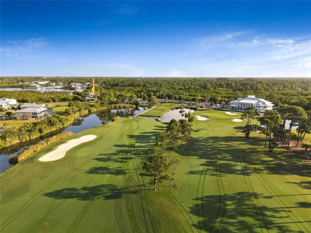 An aerial view shows a golf course with a pond and a large clubhouse building — 9720 EAGLE PRESERVE DRIVE, ENGLEWOOD, FL