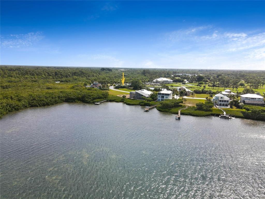 An aerial view shows waterfront homes along a coastline with a yellow arrow pointing inland — 9720 EAGLE PRESERVE DRIVE, ENGLEWOOD, FL