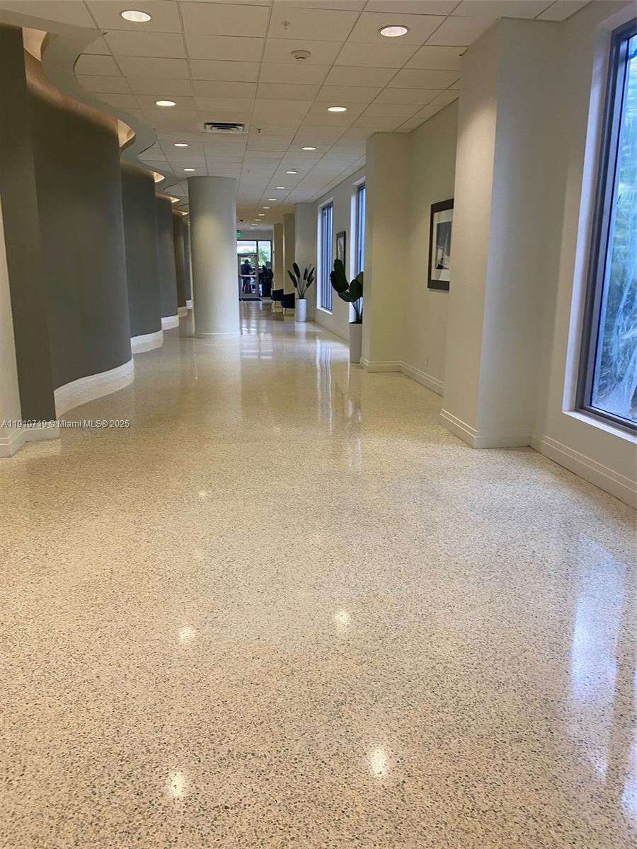A long, polished terrazzo hallway features curved walls, recessed lighting, and floor-to-ceiling windows — 4001 S Ocean Dr # 14F, Hollywood FL 33019, HOLLYWOOD, FL