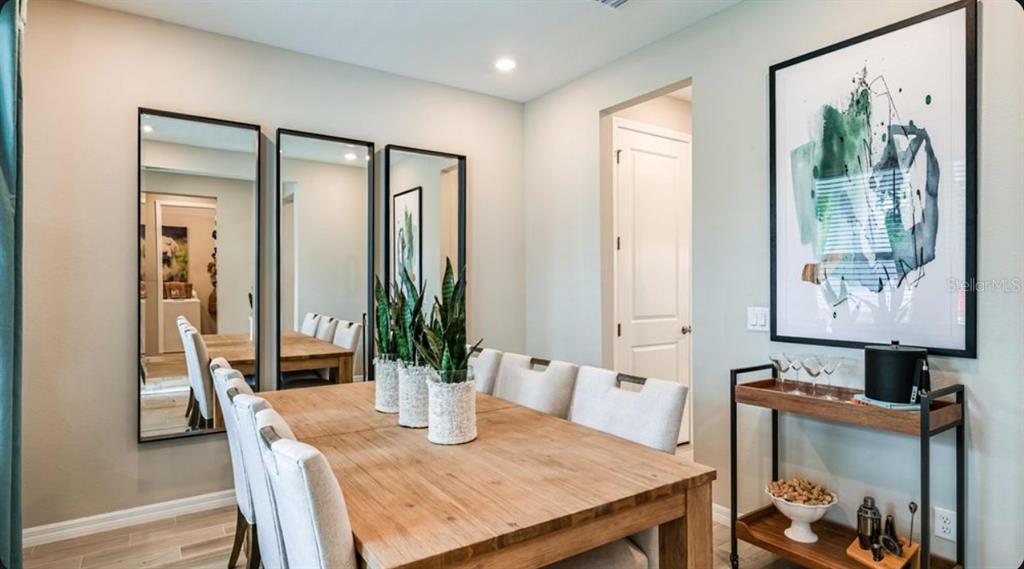 A dining room features a wooden table, upholstered chairs, three wall mirrors, and a bar cart — 5770 BINNACLE LANE, COCOA, FL