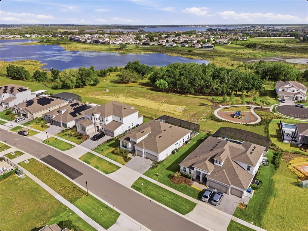 An aerial view shows a suburban neighborhood with houses, a playground, and a nearby lake — 16071 BARKLY RIDGE COURT, WINTER GARDEN, FL