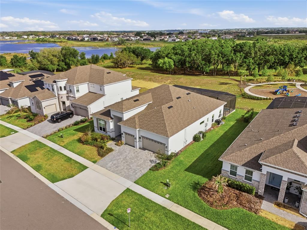 An aerial view shows suburban houses with paved driveways and screened lanais near a lake — 16071 BARKLY RIDGE COURT, WINTER GARDEN, FL