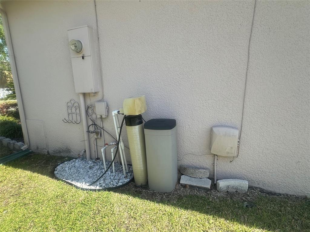 An exterior view of a house wall featuring a water softener system and electrical equipment — 14958 LAKE AZURE DRIVE, ORLANDO, FL