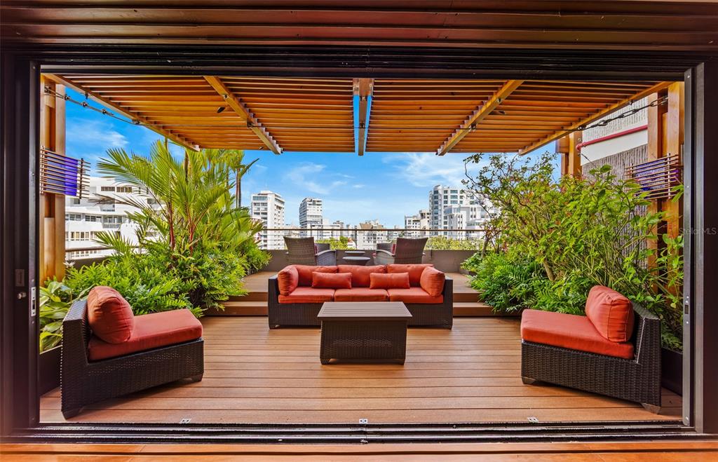 A furnished outdoor terrace features a wooden deck, a pergola, and lush potted plants — 1223 LUCHETTI STREET UNIT 801, SAN JUAN, PR