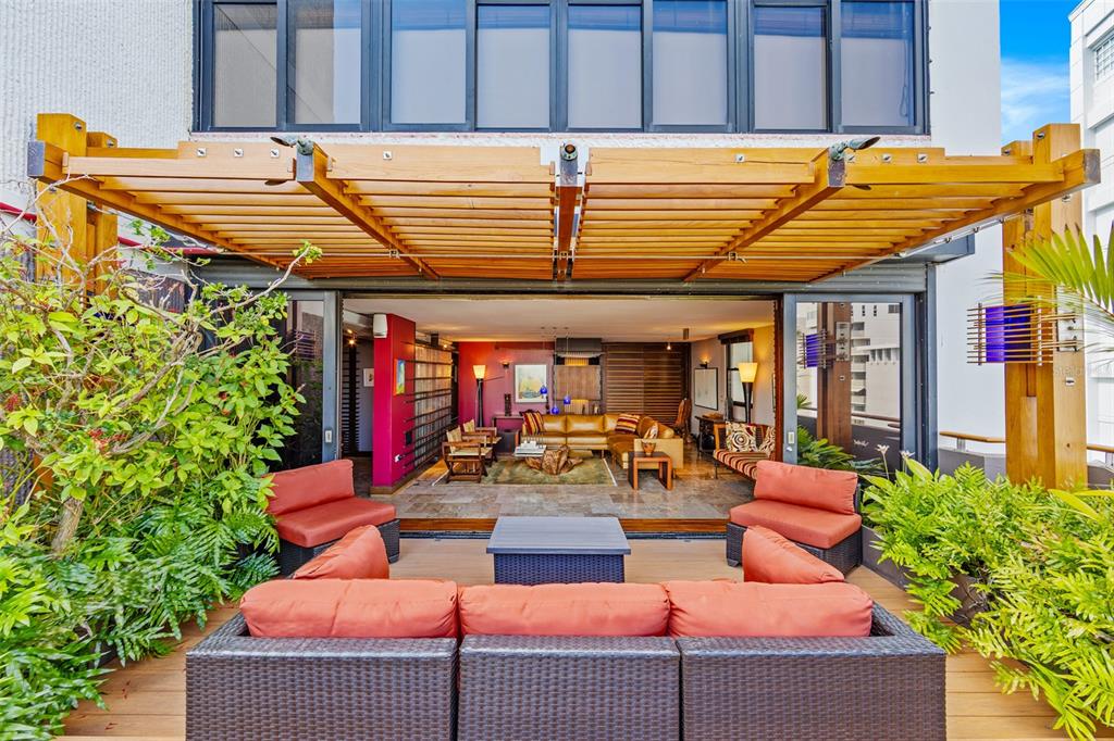 A wooden pergola covers an outdoor deck with patio furniture overlooking an open-plan living room — 1223 LUCHETTI STREET UNIT 801, SAN JUAN, PR