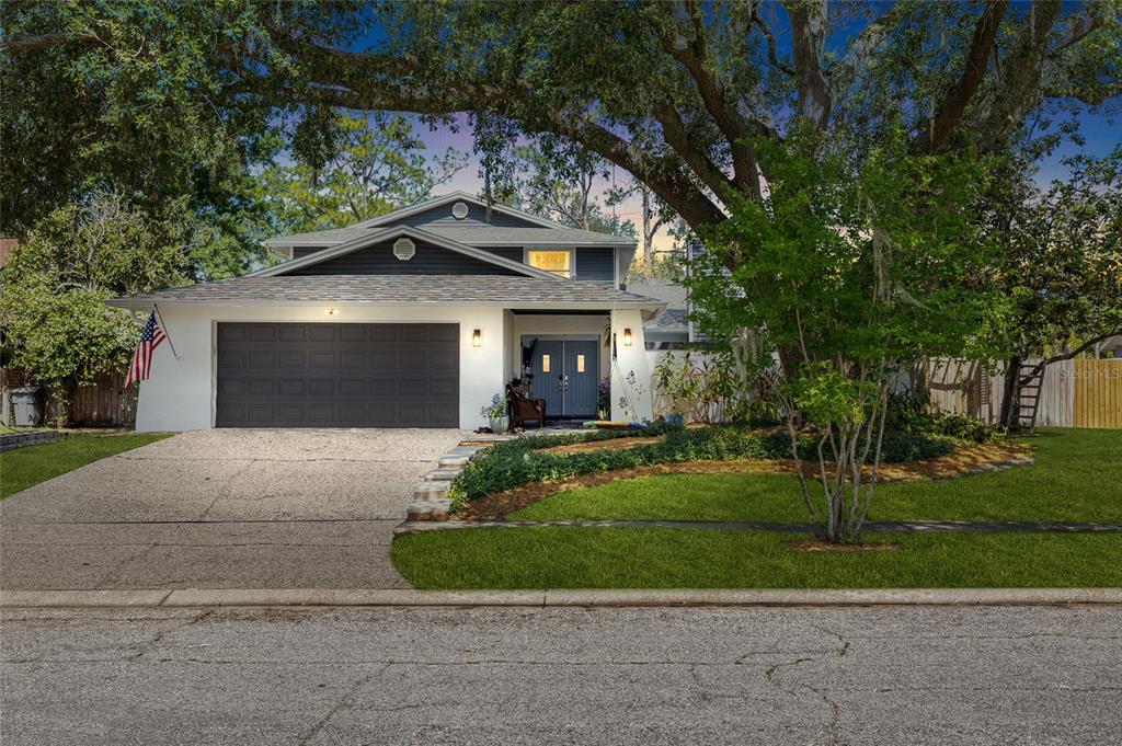 A two-story house with a white exterior, dark garage door, and a large front tree — 15620 GARDENSIDE LANE, TAMPA, FL
