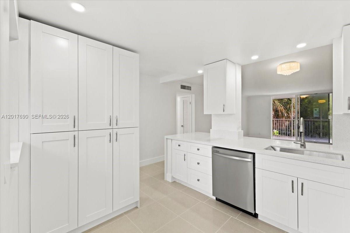 A modern kitchen features white cabinetry, stainless steel appliances, and light-colored tile flooring — 319 NE 14TH AVE # 201, Hallandale Beach FL 33009, HALLANDALE BEACH, FL