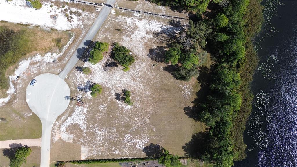 An aerial view shows a vacant, sandy lot bordering a lake and a cul-de-sac — 4094 CAMP SHORE DRIVE, SEBRING, FL