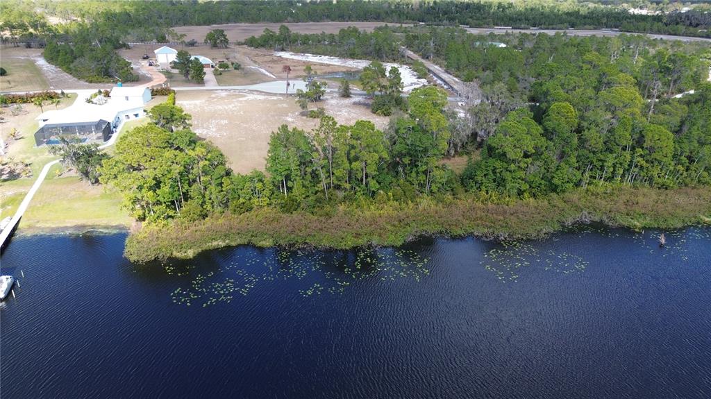 An aerial view shows a waterfront property with a house, dock, and surrounding wooded land — 4094 CAMP SHORE DRIVE, SEBRING, FL
