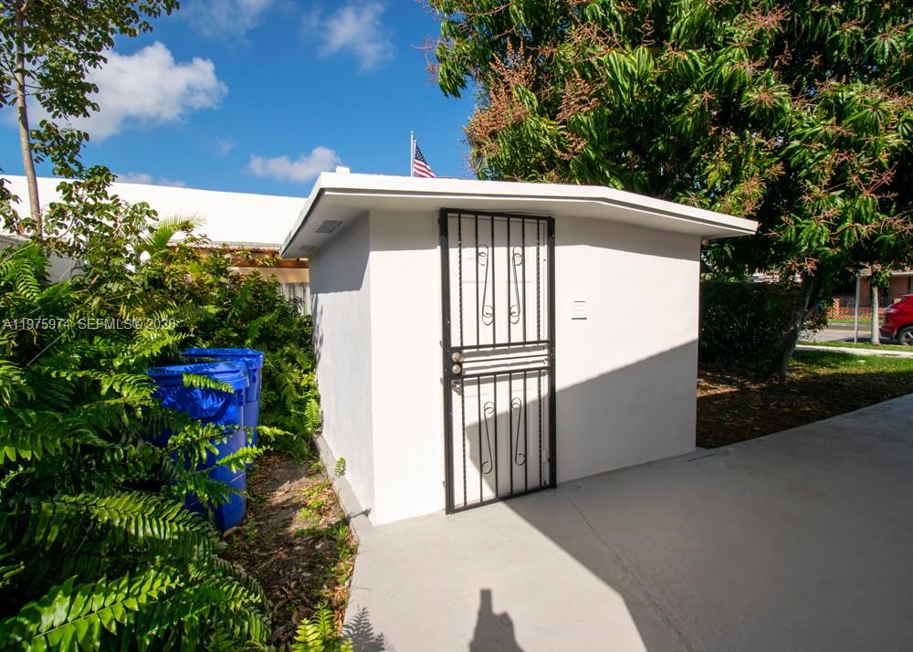 A white exterior storage shed with a black metal security door sits on concrete — 3200 SW 2nd St, Miami FL 33135, MIAMI, FL