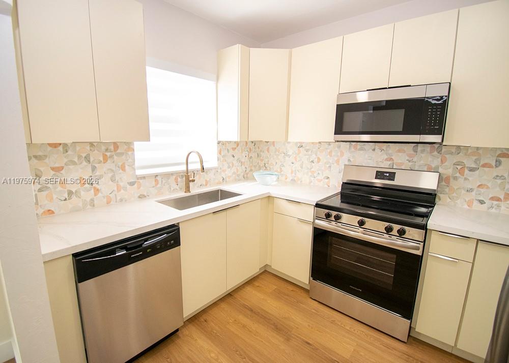 A kitchen features light-colored cabinets, stainless steel appliances, and a patterned tile backsplash — 3200 SW 2nd St, Miami FL 33135, MIAMI, FL