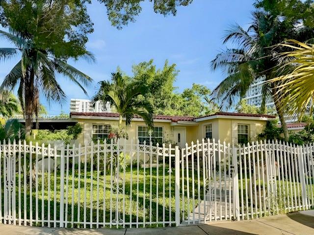 A yellow single-story house is viewed from behind a white metal fence with palm trees — 2701 SW 29th Ave, Miami FL 33133, MIAMI, FL