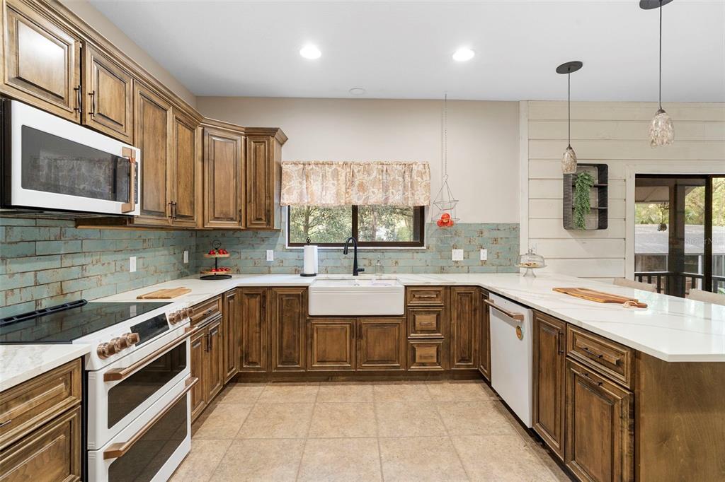 A kitchen features wood cabinets, a farmhouse sink, white countertops, and a blue tile backsplash — 1268 MCGREGOR ROAD, DELAND, FL