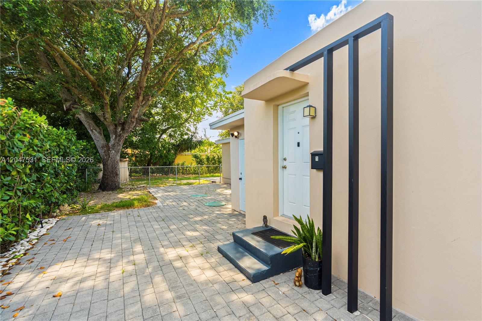 A paved patio leads to a white front door with black decorative vertical beams — 5800 Taylor St # 1, Hollywood FL 33021, HOLLYWOOD, FL