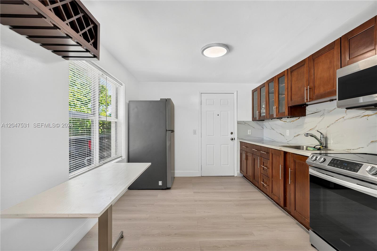 A kitchen features wood cabinets, stainless steel appliances, white countertops, and a light wood floor — 5800 Taylor St # 1, Hollywood FL 33021, HOLLYWOOD, FL