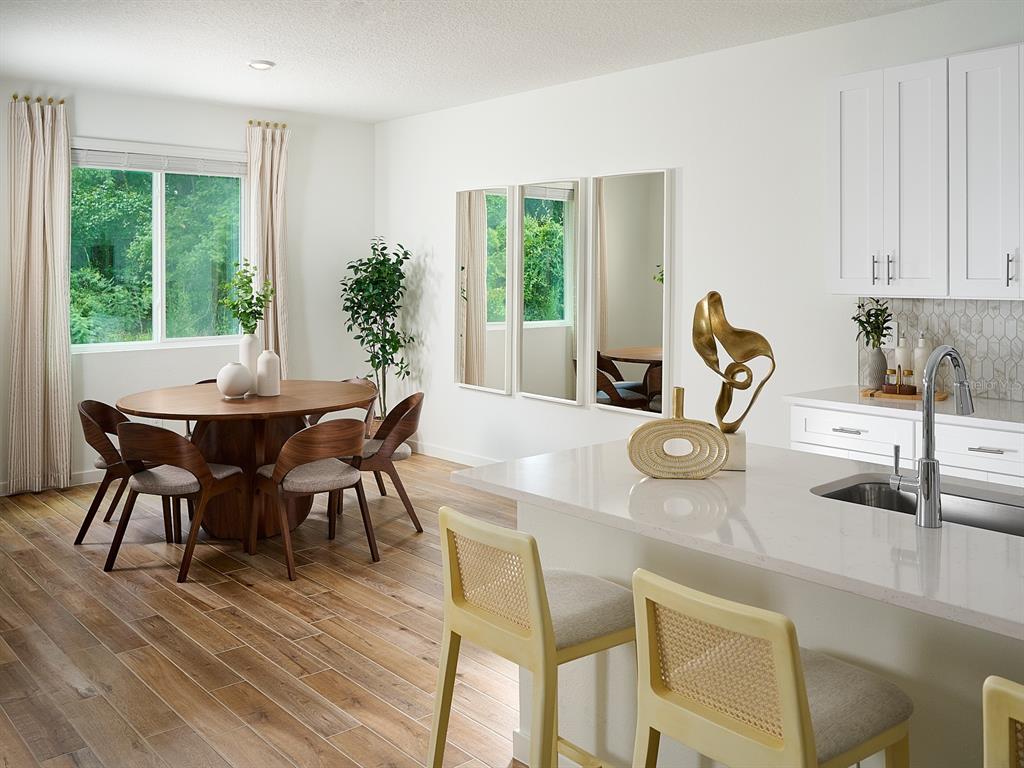 A dining area with a round wooden table and kitchen island with light-colored stools — 98 TEQUESTA COURT, PALM COAST, FL