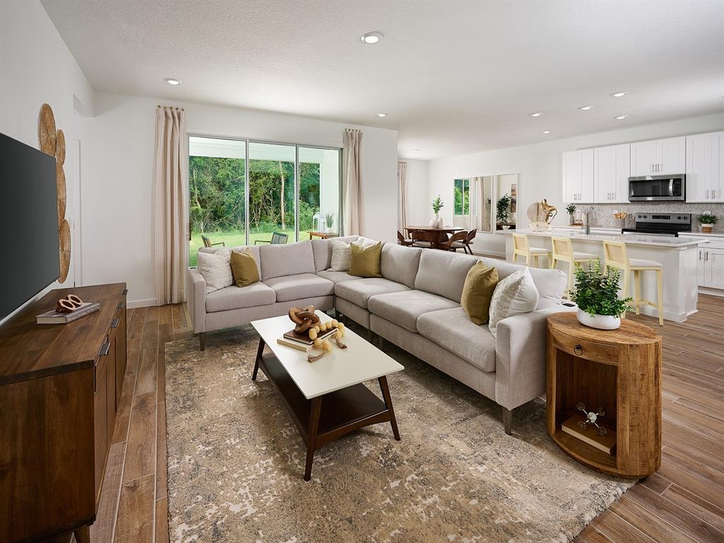 A living room with a sectional sofa, coffee table, and open kitchen in the background — 98 TEQUESTA COURT, PALM COAST, FL