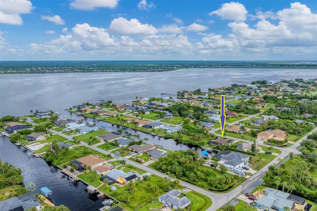 An aerial view shows a waterfront residential neighborhood with a yellow arrow pointing to a house — 2555 DIXON TERRACE, PORT CHARLOTTE, FL
