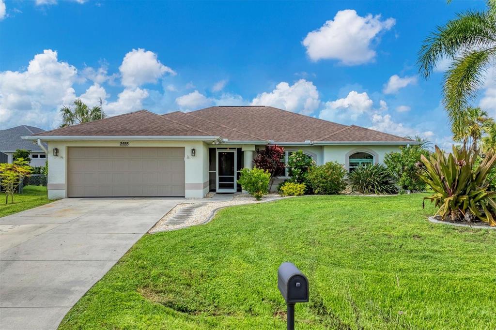 A single-story house with a beige exterior, a two-car garage, and a landscaped front lawn — 2555 DIXON TERRACE, PORT CHARLOTTE, FL