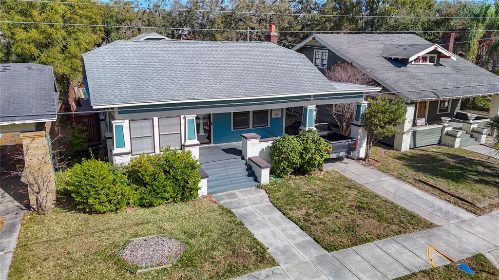 An aerial view shows a teal bungalow with a front porch and a paved driveway — 2105 W SOUTHVIEW AVENUE, TAMPA, FL