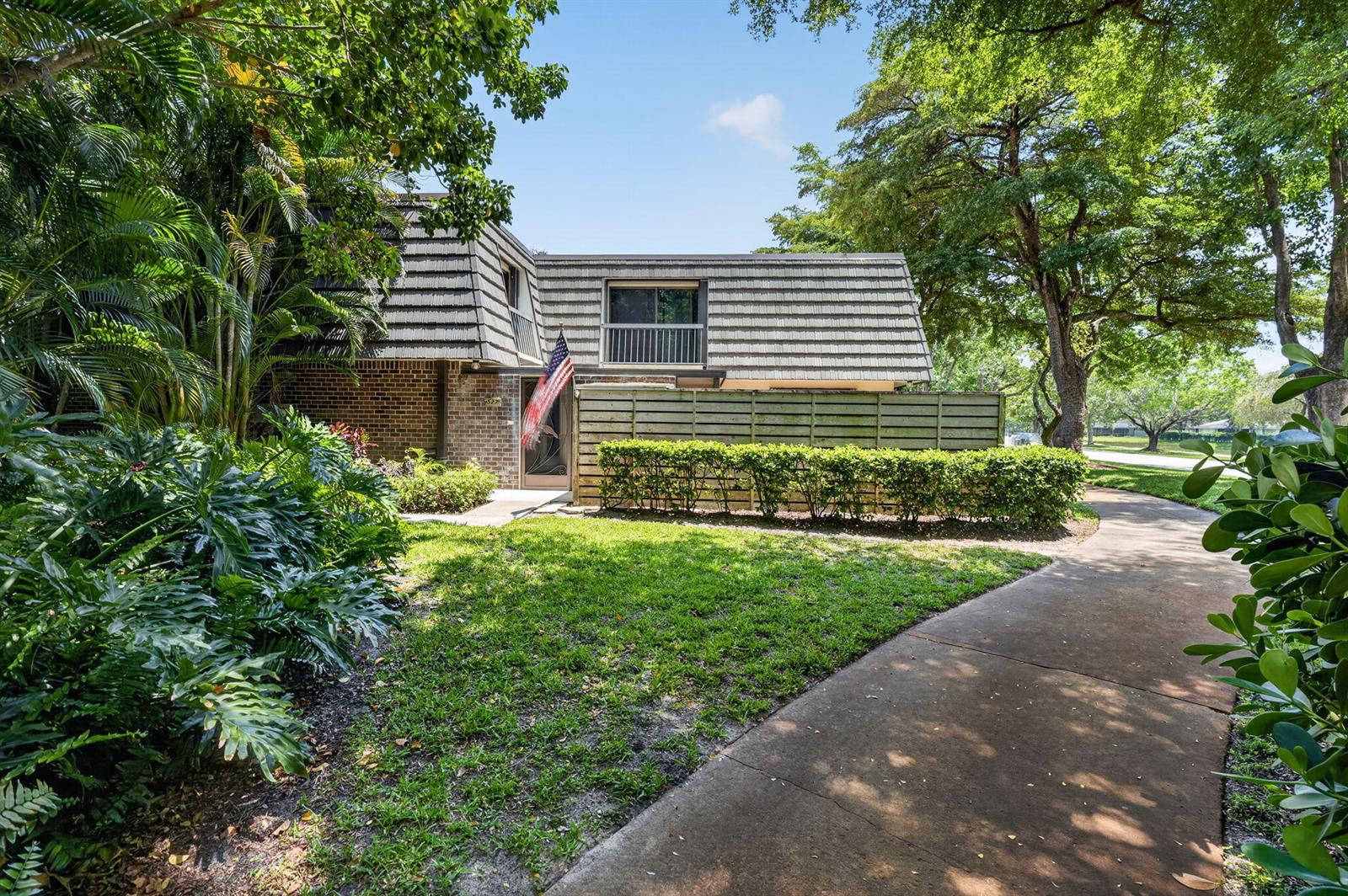 A two-story townhouse with a mansard roof, brick facade, and a wooden privacy fence — 527 5th Terrace, Palm Beach Gardens FL 33418, PALM BEACH GARDENS, FL