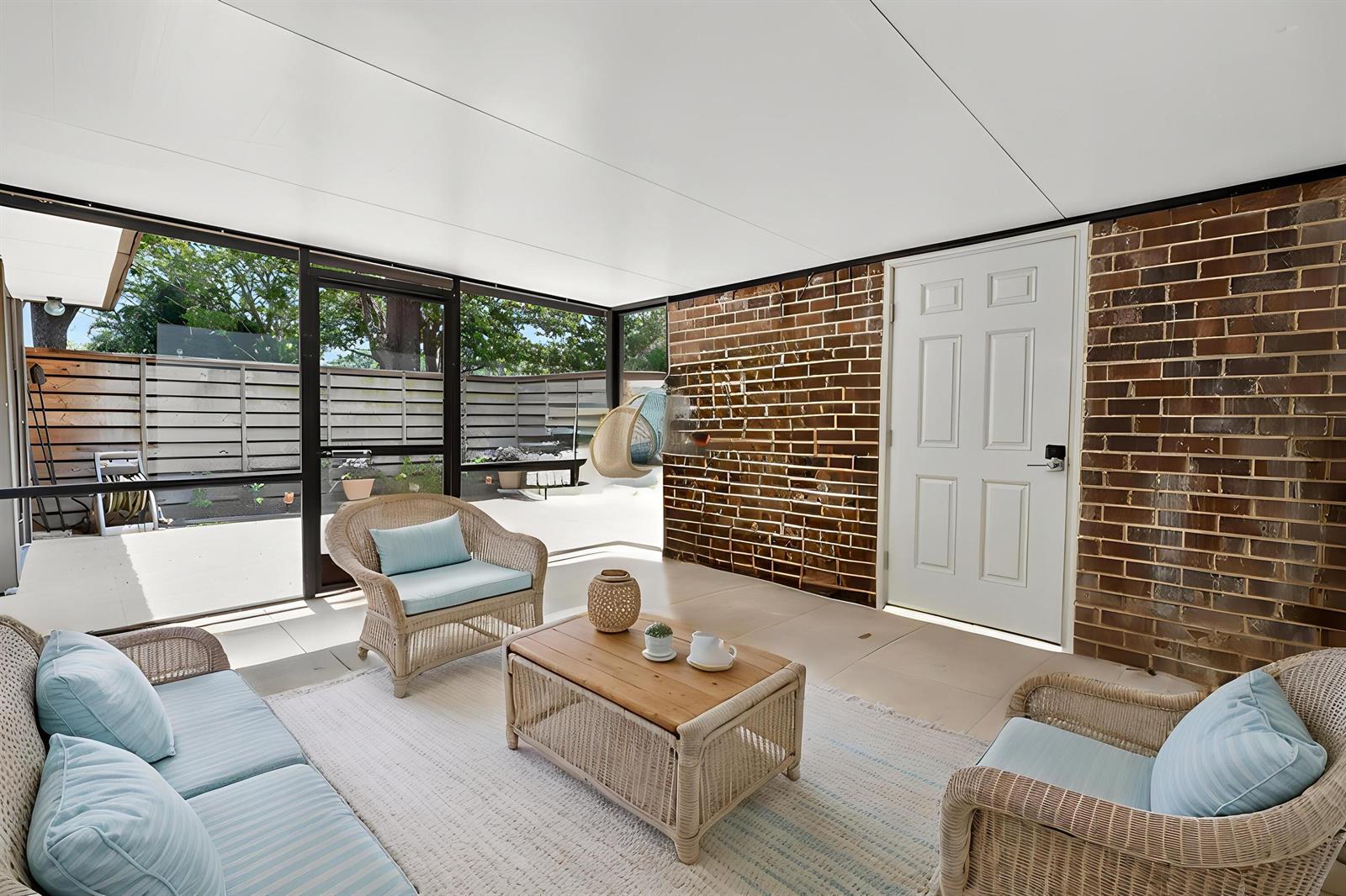 A sunroom features wicker furniture, a brick wall, and a white door leading outside — 527 5th Terrace, Palm Beach Gardens FL 33418, PALM BEACH GARDENS, FL
