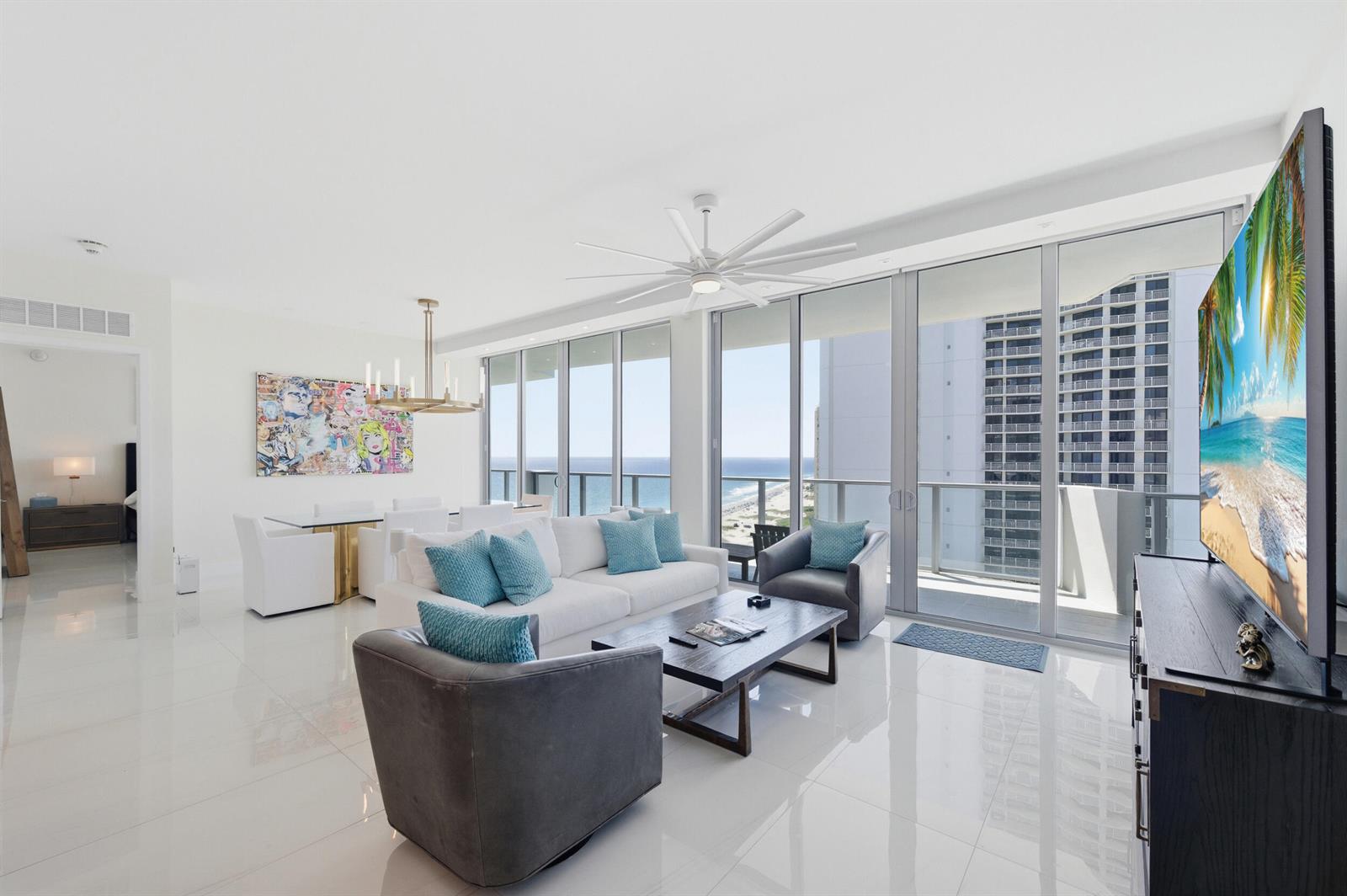 A modern living room with white tile floors, a white sofa, and floor-to-ceiling balcony windows — 3100 N Ocean Drive # 1506, Singer Island FL 33404, SINGER ISLAND, FL