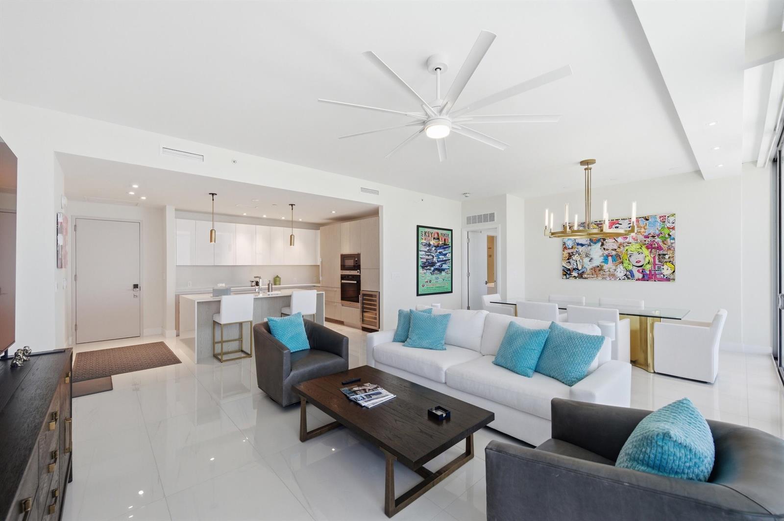 A modern open-concept living room and kitchen featuring white tile floors and a ceiling fan — 3100 N Ocean Drive # 1506, Singer Island FL 33404, SINGER ISLAND, FL