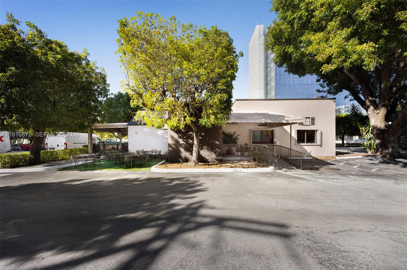 A low-rise commercial building features an outdoor patio area with tables and mature trees — 2345 SW 37th Ave, Miami FL 33145, MIAMI, FL