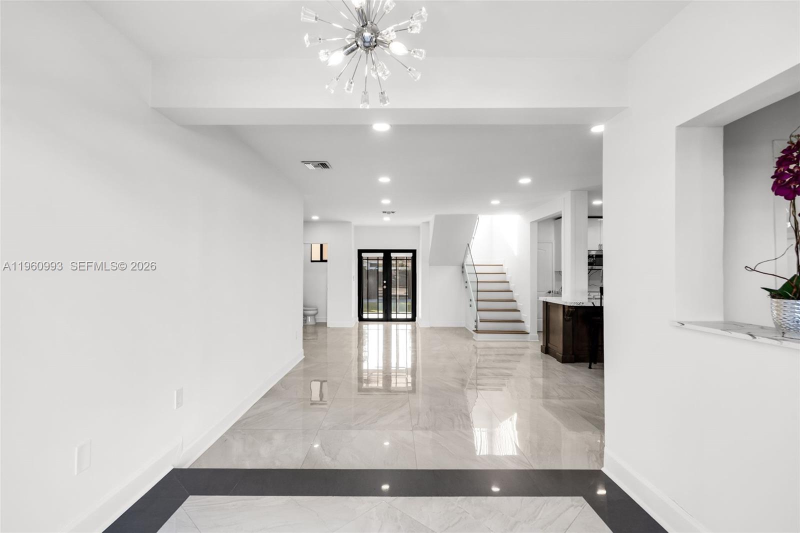 A bright, open-concept living area features white walls, polished tile floors, and a modern staircase — 66 NW 73rd Place, Miami FL 33126, MIAMI, FL