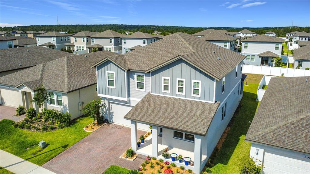 An aerial view shows a two-story suburban house with a paved driveway and landscaping — 2271 BEAR PEAK ROAD, MINNEOLA, FL