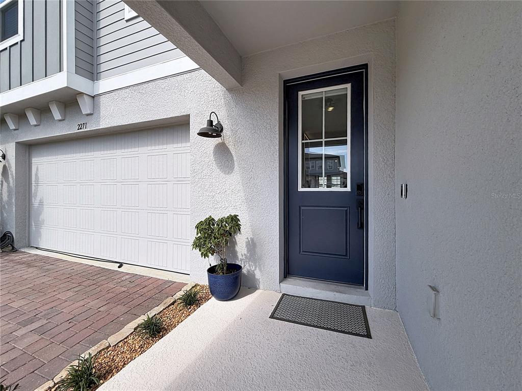 A blue front door with a glass pane sits next to a white garage door — 2271 BEAR PEAK ROAD, MINNEOLA, FL