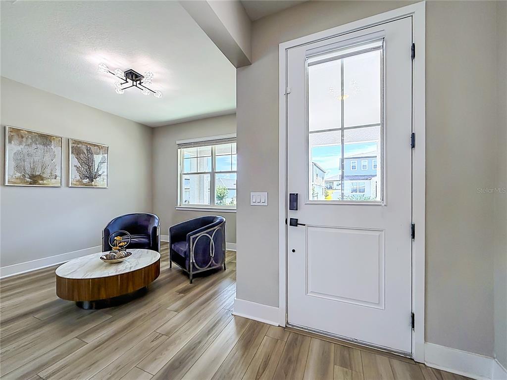A bright entryway features wood-look flooring, a white front door, and a small seating area — 2271 BEAR PEAK ROAD, MINNEOLA, FL