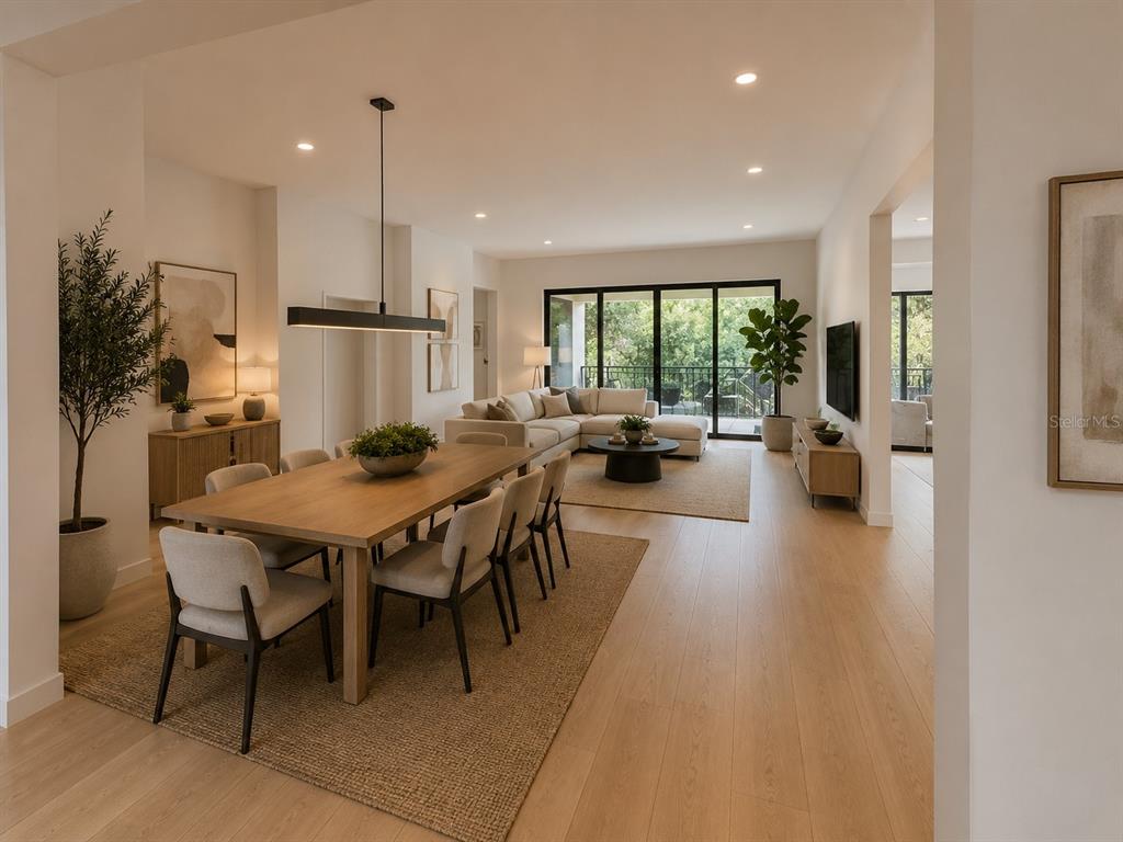 An open-concept dining and living area features light wood flooring, modern furniture, and large windows — 5020 W HOMER AVENUE, TAMPA, FL