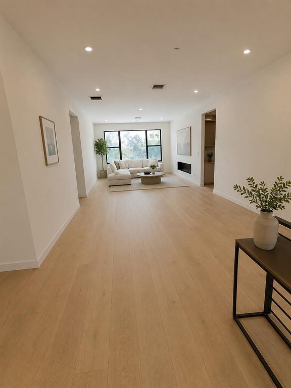 A bright, minimalist living room features light wood flooring, a sectional sofa, and a fireplace — 5020 W HOMER AVENUE, TAMPA, FL