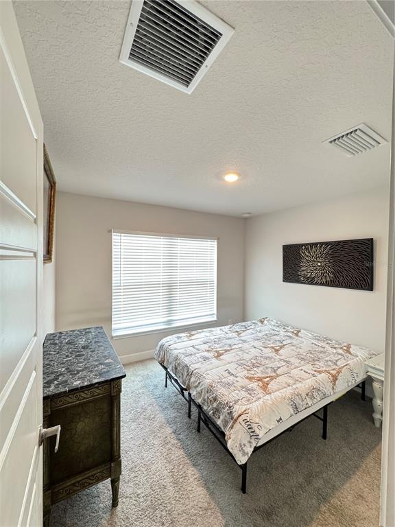 A bedroom features a bed with a patterned quilt, a dresser, and a window — 5380 LUGO STREET, FORT PIERCE, FL