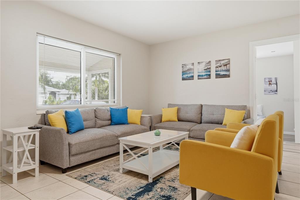 A living room features two gray sofas, two yellow armchairs, and a white coffee table — 14512 117TH AVENUE, LARGO, FL