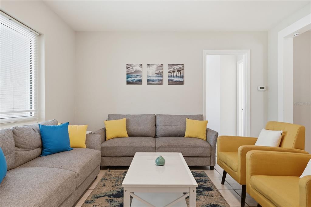 A living room features two gray sofas, two yellow armchairs, and a white coffee table — 14512 117TH AVENUE, LARGO, FL