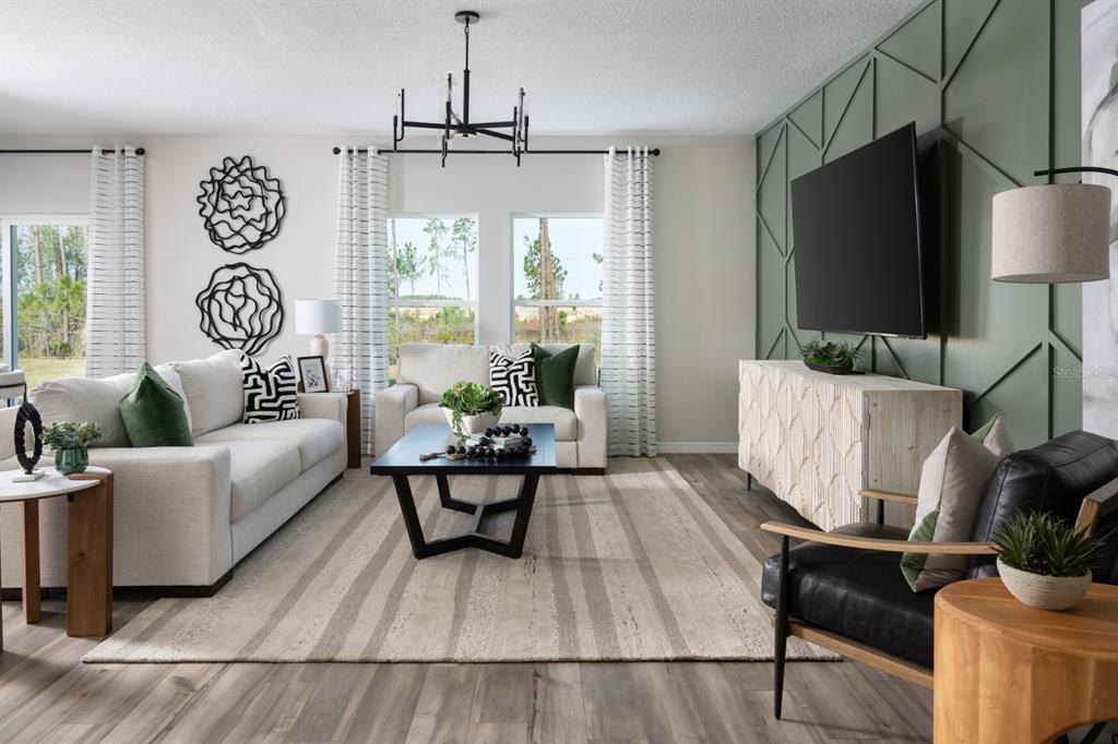 A living room features a green accent wall with molding, a television, and neutral furniture — 5386 SAN PIETRO DRIVE, WINTER HAVEN, FL
