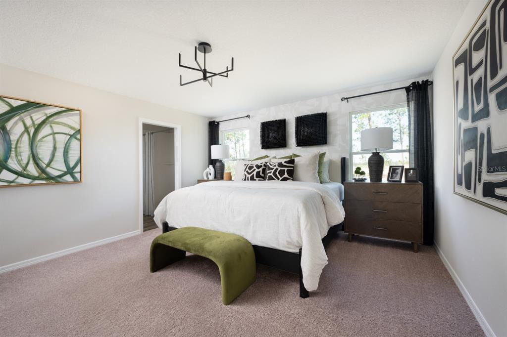 A bedroom features a bed with patterned pillows, a green bench, and two large wall artworks — 5386 SAN PIETRO DRIVE, WINTER HAVEN, FL