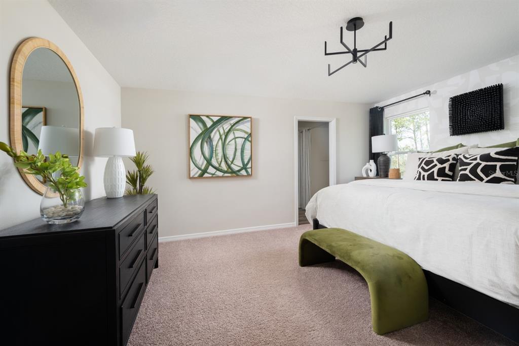 A bedroom features a black dresser, a bed with patterned pillows, and a green bench — 5386 SAN PIETRO DRIVE, WINTER HAVEN, FL