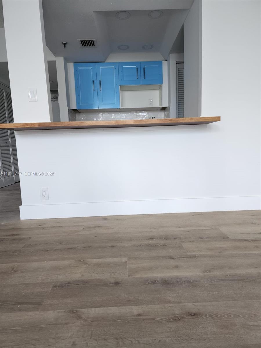 A kitchen features bright blue cabinets above a wooden breakfast bar and wood-look flooring — 520 Brickell Key Dr # A1517, Miami FL 33131, MIAMI, FL