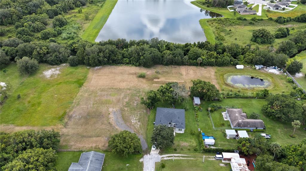 An aerial view shows a large, grassy lot with a house and a small pond — 1819 KENTUCKY AVENUE, ST CLOUD, FL