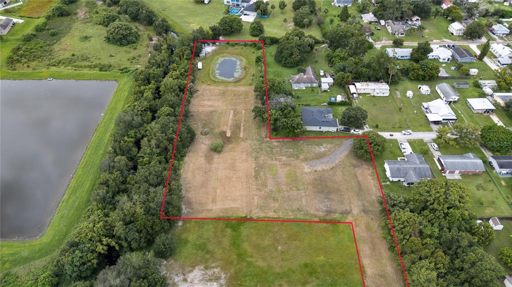 An aerial view shows a large, vacant rectangular lot outlined in red with a small pond — 1819 KENTUCKY AVENUE, ST CLOUD, FL