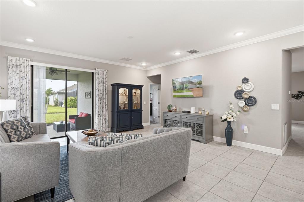 A living room features gray furniture, a blue area rug, and a dark blue display cabinet — 15240 MILLE FIORE BOULEVARD, PORT CHARLOTTE, FL