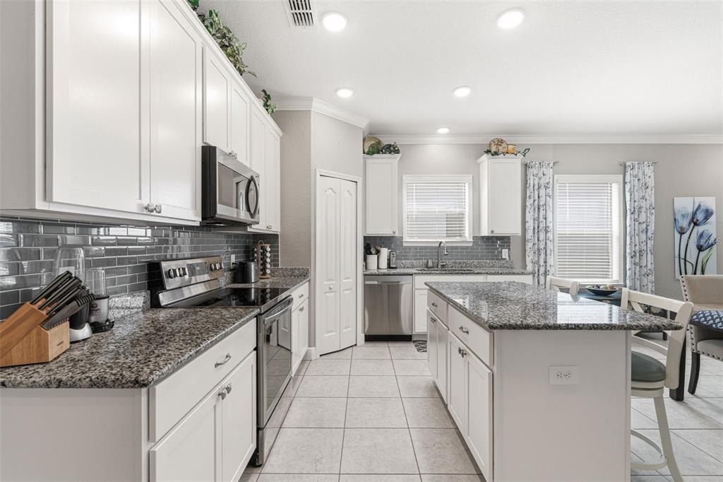 A kitchen with white cabinets, granite countertops, stainless steel appliances, and a gray subway tile backsplash — 15240 MILLE FIORE BOULEVARD, PORT CHARLOTTE, FL